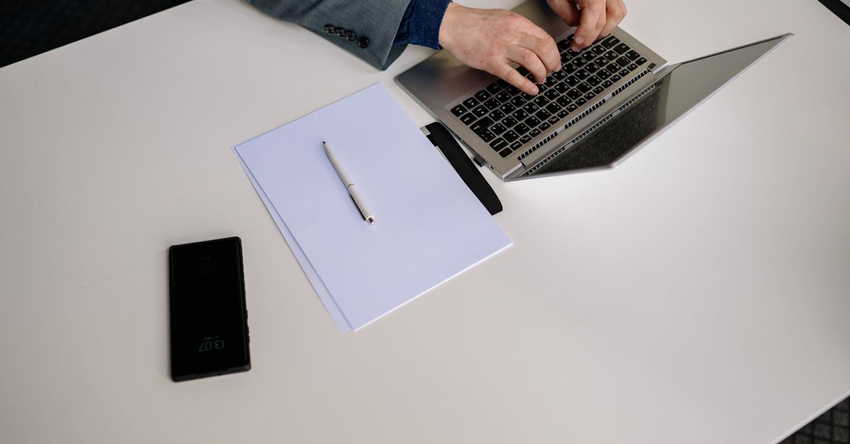 A consultant's desk with a laptop and blank report pages, preparing findings after a CHECK penetration test