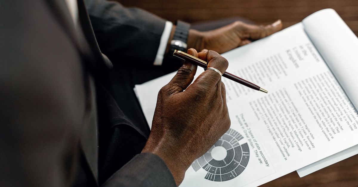 A compliance document being reviewed by hand, reflecting the readiness checks the Cyber Security and Resilience Bill expects businesses to prove