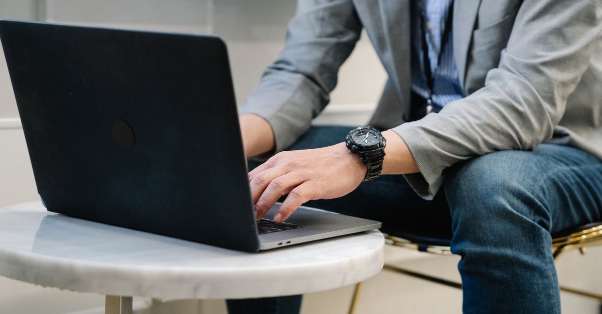A consultant typing on a laptop, reviewing the scope of an authorised penetration test