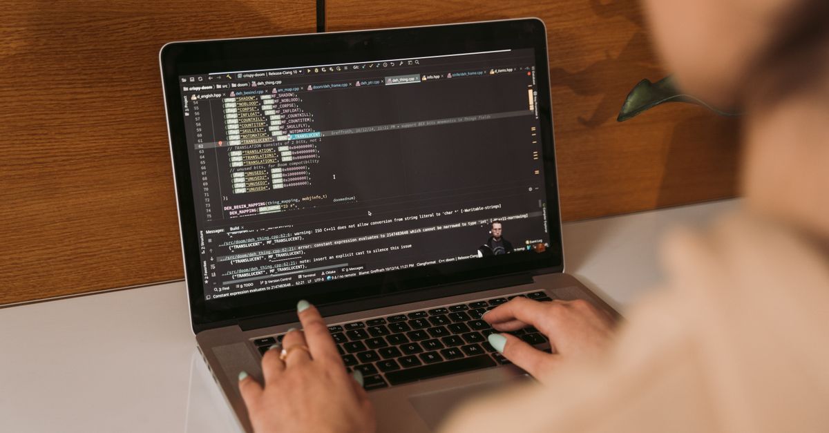 A developer's hands typing on a laptop showing code, illustrating the VS Code extension vulnerability at the centre of the disclosure