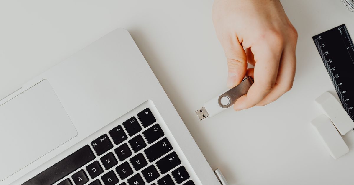 A hand plugging a USB drive into a laptop to back up files against ransomware