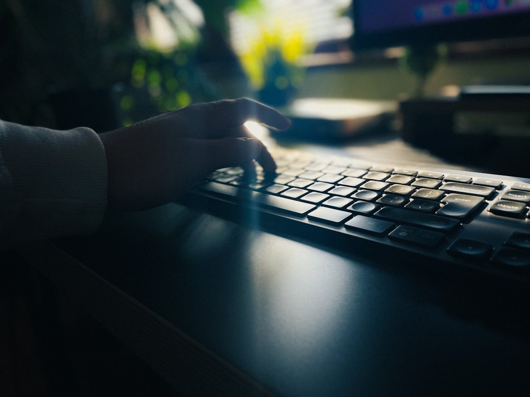 A hand typing on a keyboard in low light, representing the quiet reconnaissance stage a ClickFix attack relies on going unnoticed