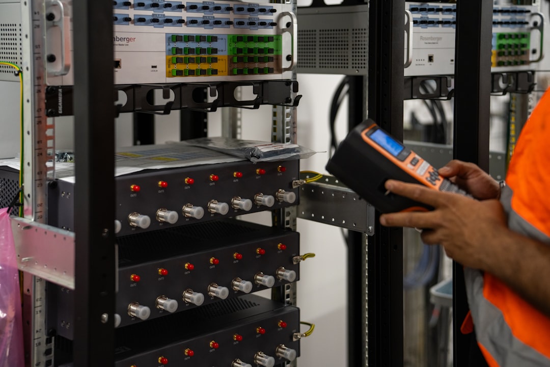 A technician inspecting a network patch panel with a diagnostic tool, checking edge devices for exposure