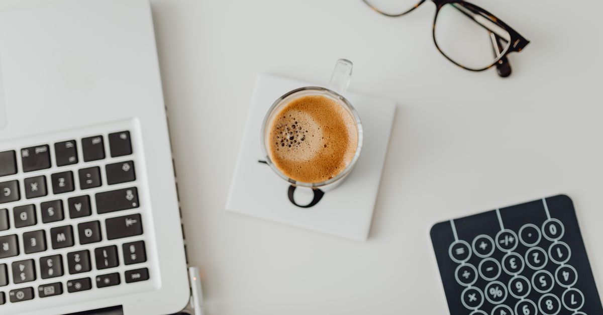 A tidy office desk with a laptop, coffee and glasses, representing the routine patch check every business needs after the cPanel database vulnerability