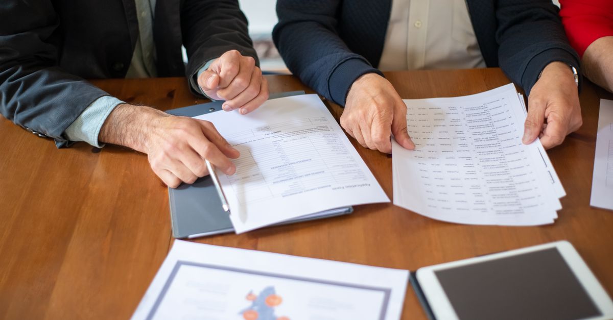 Business colleagues reviewing contract paperwork, the kind of EU customer agreement that can bring NIS2 penetration testing requirements to a UK supplier