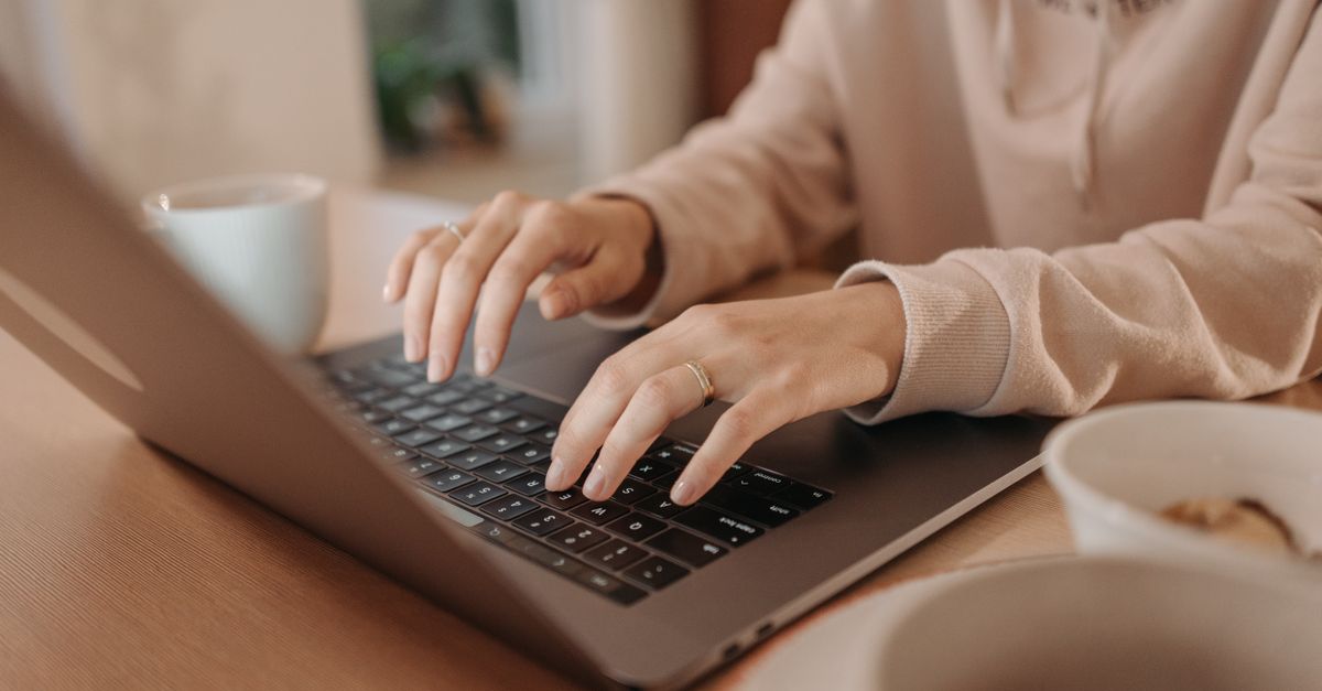 Close-up of hands typing on a laptop keyboard, resetting a password after the Keycloak password reset flaw