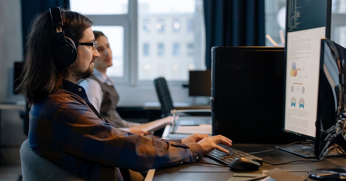 IT professional at a desk reviewing monitors, representing the Dahua camera security audit businesses now need to run
