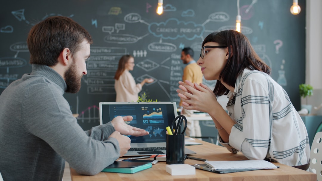 Two colleagues reviewing security data on a laptop together in an office, discussing how ransomware works and what to check