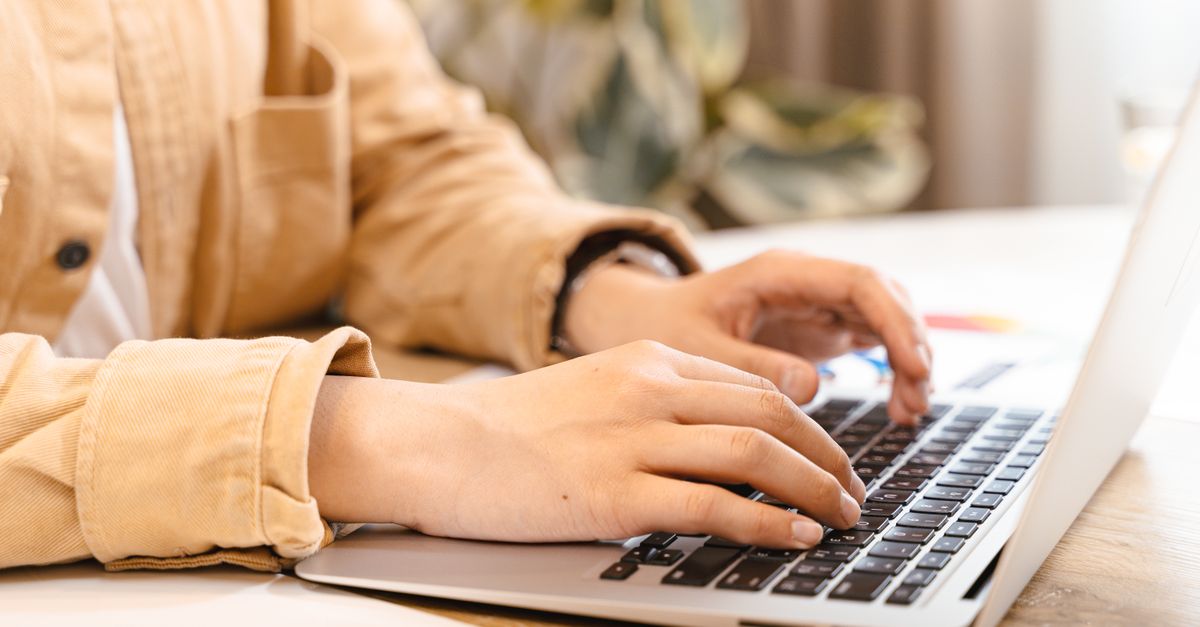 A staff member's hands typing on a laptop keyboard in an office, the kind of routine access an insider threat can misuse