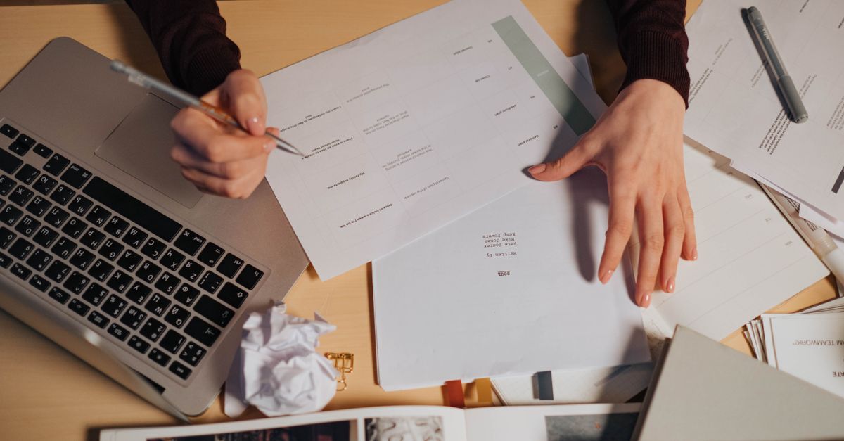 Accountant working through client paperwork beside a laptop before penetration testing for accountancy firms