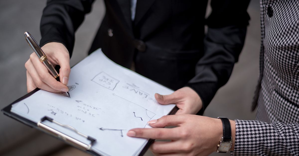 Business colleagues reviewing quote figures on a clipboard before budgeting for a vulnerability assessment