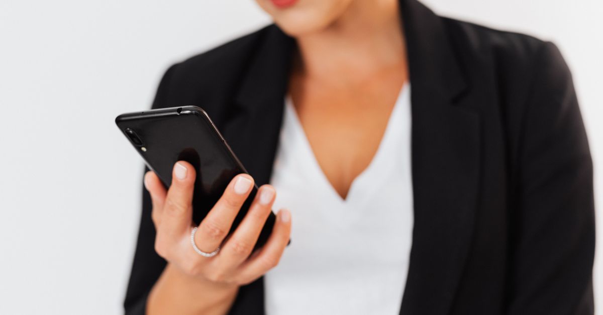Business professional in an office checking a smartphone, part of monitoring for credential stuffing attempts