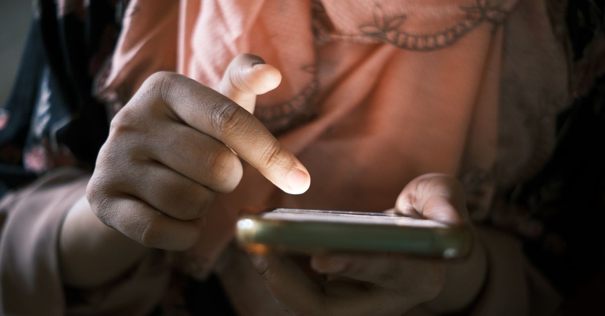 Close-up of a hand tapping a smartphone screen to approve a multi-factor authentication prompt
