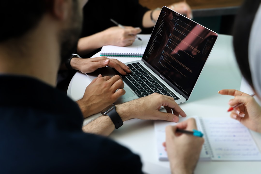 Colleagues reviewing code on a laptop screen while patching a hard-coded key vulnerability