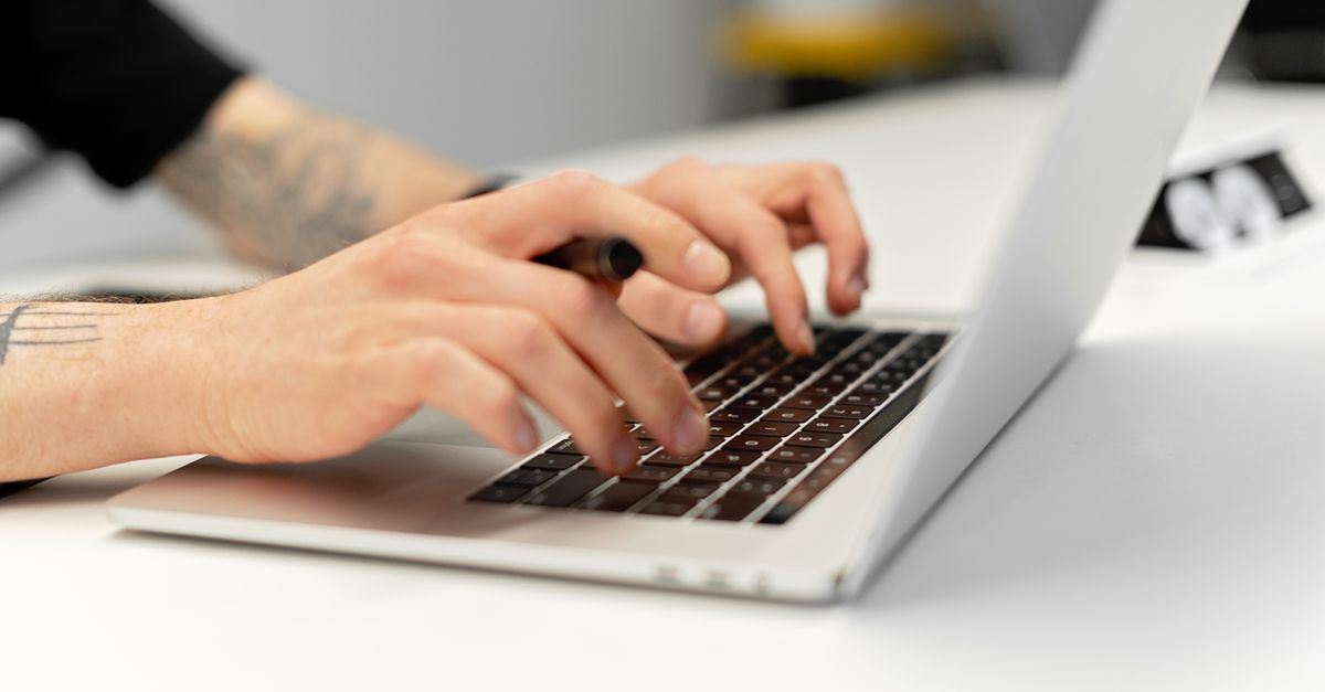 Hands typing on a laptop keyboard while updating a business website's plugins