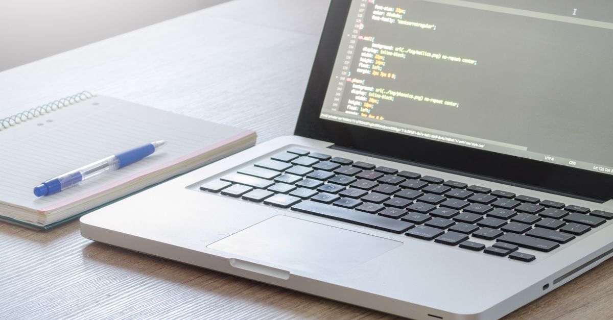 Laptop displaying source code beside a notebook and pen, representing the software installer chain an EDR killer driver hides inside