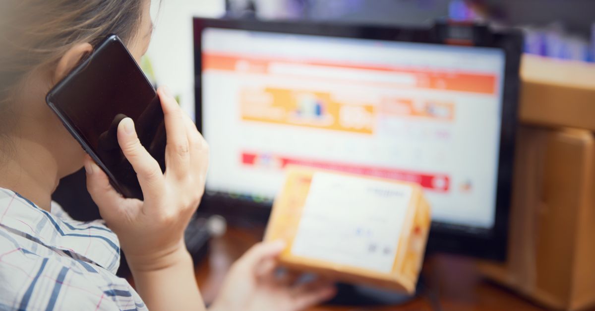 Online shopper on the phone with a delivery box in front of a retailer's website, the kind of customer data an ecommerce penetration test aims to protect