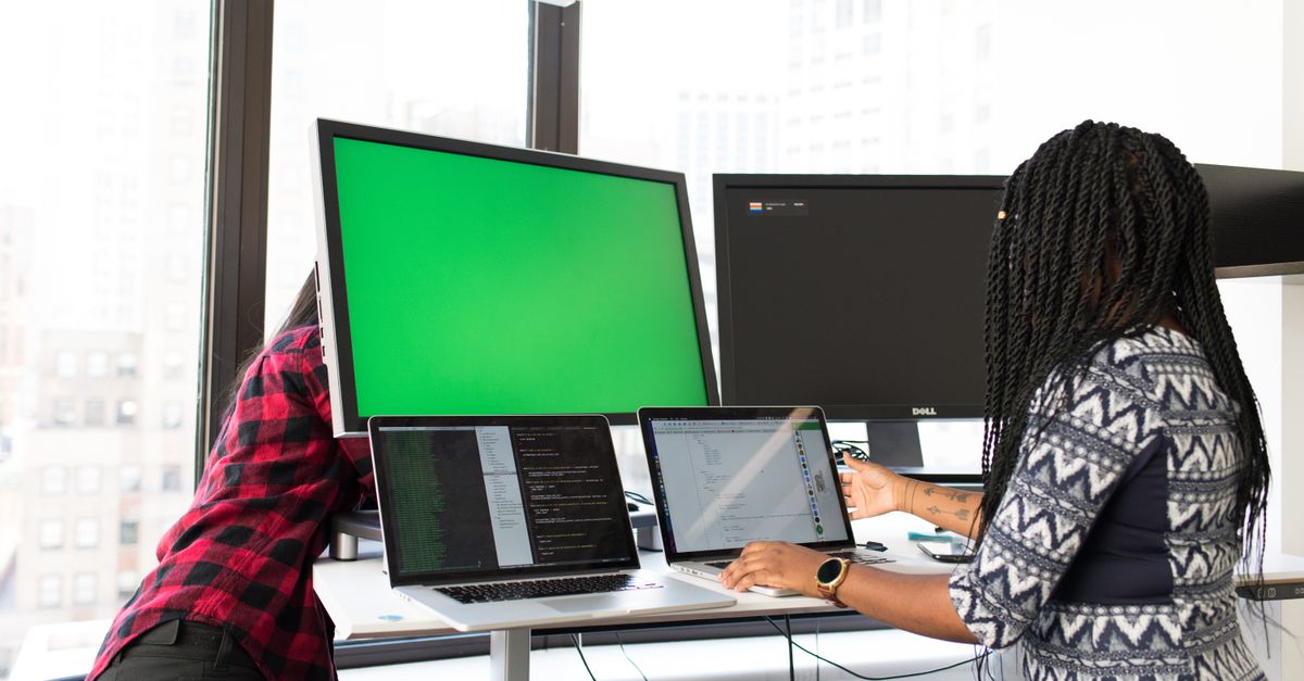 Two colleagues working on mismatched, unmanaged laptops and monitors