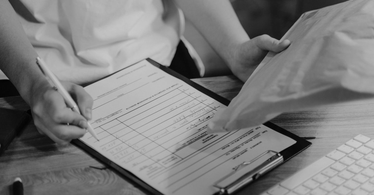 Two colleagues working through a checklist on a clipboard at a desk