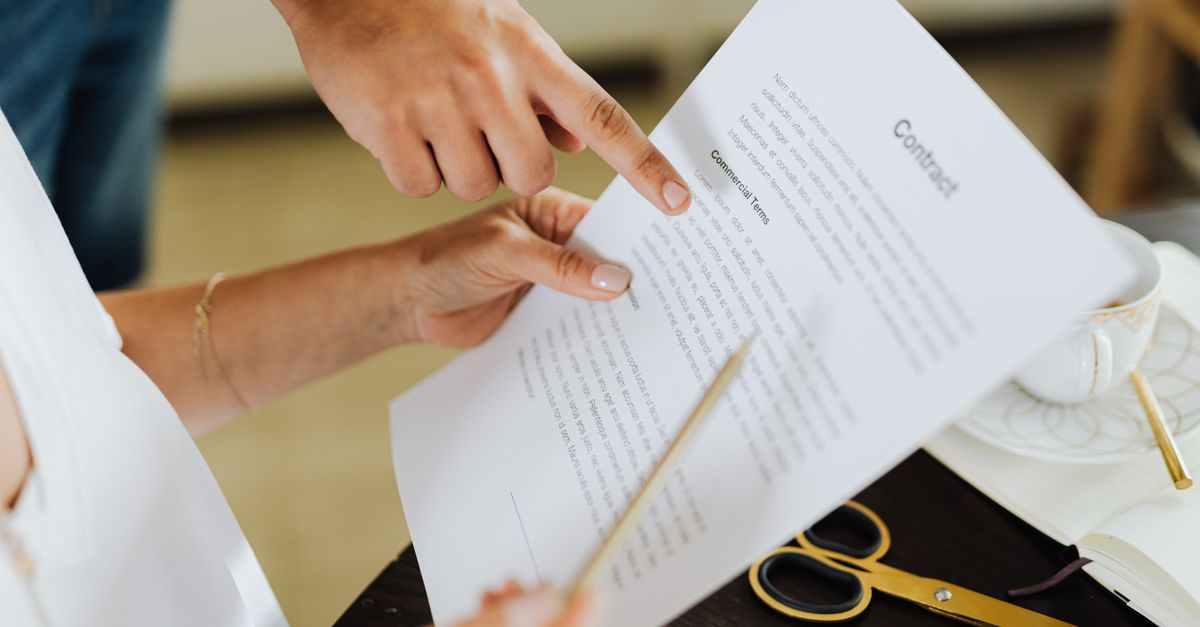 Two people pointing at commercial terms on a penetration testing contract before signing