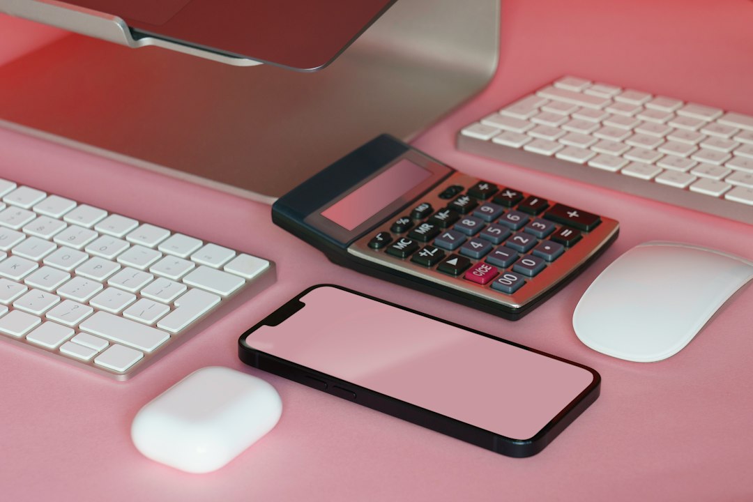 Calculator beside keyboards and a phone, representing the cost of Cyber Essentials for office kit